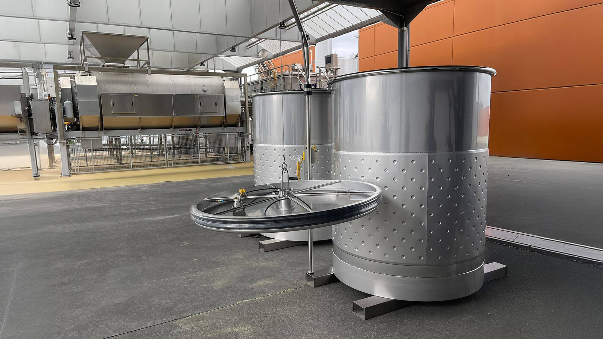 multi-06 Two stainless-steel wine tanks with dimple jackets and a variable-capacity lid are set up in a modern winery space.